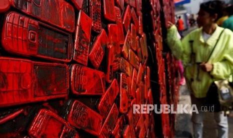 Seorang model berpose dengan latar belakang karya instalasi limbah ponsel yang diprakarsai oleh Greenpeace Indonesia ketika pelaksanaan Hari Bebas Kendaraan Bermotor (HBKB) di Kawasan Bundaran HI Jakarta, Minggu (26/2).