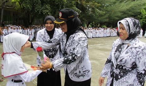 Seorang murid menghadiahkan bunga kepada gurunya saat upacara peringatan Hari Guru Nasional di SDN 1 Banda Aceh, Rabu (25/11).