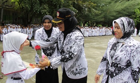 Seorang murid menghadiahkan bunga kepada gurunya saat upacara peringatan Hari Guru Nasional di SDN 1 Banda Aceh, Rabu (25/11). (Antara/Ampelsa)