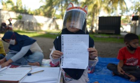 Seorang murid PAUD menunjukan selembar kertas hasil pelajarannya saat mengikuti proses belajar mengajar di sebuah pekarangan rumah, Desa Lamprit, Kecamatan Kuta Alam, Banda Aceh, Aceh, Jumat (7/8/20200). Aktivitas mengajar dan belajar secara sukarela yang diikuti murid PAUD, TK, SD dan SMP dengan jadwal tiga kali seminggu tersebut digelar oleh sukarelawan untuk membantu keberlangsungan pendidikan anak yang terdampak COVID-19 dengan tetap menerapkan protokol kesehatan.