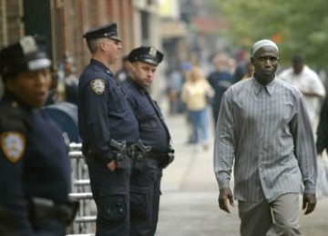 Seorang Muslim berjalan melintas di depan petugas polisi kota New York (NYPD) yang sedang bertugas.