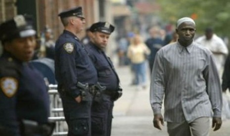 Seorang Muslim berjalan melintas di depan petugas polisi kota New York (NYPD) yang sedang bertugas.