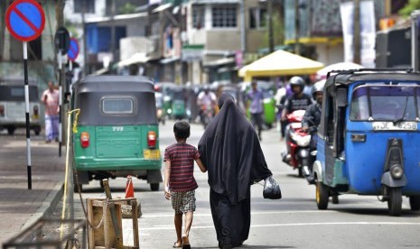 Seorang Muslim Sri Lanka dan putranya berjalan setelah dari pasar di Kolombo, Sri Lanka, Senin (29/4). Sri Lanka resmi melarang penggunaan cadar.