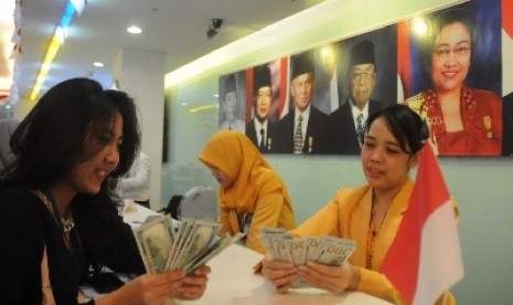   Seorang nasabah bersama dengan pegawai Bank Mandiri sedang menghitung uang lembaran dolar AS di Jakarta, Rabu (12/8).