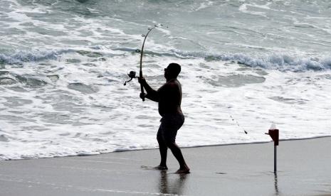 Seorang nelayan melemparkan umpannya ke Samudera Atlantik di Pantai Playalinda di Canaveral National Seashore Selasa, 30 Agustus 2022, di Titusville, Florida, Amerika Serikat. Badan cuaca PBB memperkirakan bahwa fenomena yang dikenal sebagai La Nina akan berlangsung hingga akhir tahun ini.  