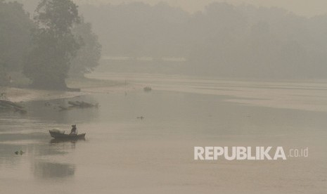 Seorang nelayan mencari ikan di tengah pekatnya kabut asap dampak dari karhutla yang menyelimuti kawasan sungai Siak di Pekanbaru, Riau, Kamis (19/9/2019).