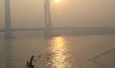 Seorang nelayan menjala ikan di Sungai Musi saat kabut asap menyelimuti Kota Palembang, Selasa (6/9).