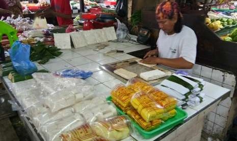 Seorang pedagang, Becky (30 tahun) di Pasar Tebet Barat, Kamis (6/9) tengah mengiris tempe untuk dibungkus dengan daun pisang. Harga tempe dan tahu belum mengalami kenaikan meski rupiah terus melemah dan memicu kenaikan harga kedelai impor. Pedagang memilih untuk mengecilkan ukuran agar keuntungan yang diperoleh tetap sama.  