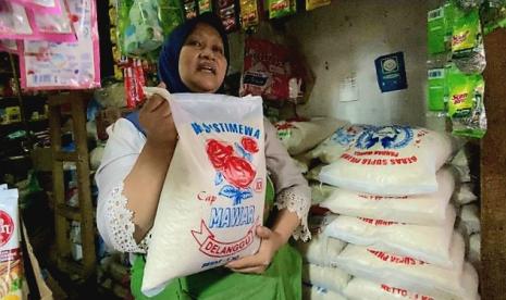   Seorang pedagang beras di Pasar Bandarjo, Ungaran, Kabupaten Semarang, Jawa Tengah, menunjukkan produk beras kemasan (sak) 5 kilogram yang harganya mengalami kenaikan hingga Rp 5.000 per sak.