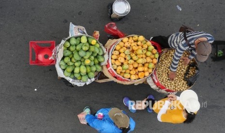 [Ilustrasi] Seorang pedagang buah melayani konsumennya.