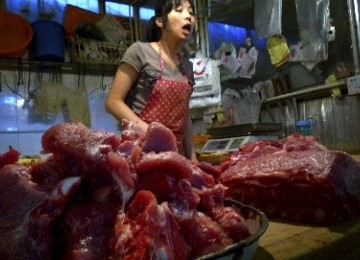 Seorang pedagang daging babi melayani pembeli di sebuah pasar kecil di Beijing, China. 