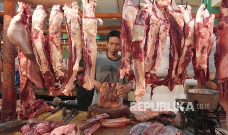 Seorang pedagang daging sedang memotong rusuk sapi (Ilustrasi)