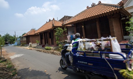 Seorang pedagang keliling melintas di depan deretan rumah bergaya arsitektur Majapahit di Desa Bejijong, Kawasan Cagar Budaya Nasional Trowulan, Mojokerto, Jawa Timur, Kamis (10/3).