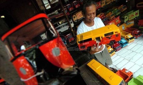 Seorang pedagang mainan mobil kayu, Umar (73) merapikan mainan yang ia jual di Jalan Raya Pasar Minggu, Jakarta Selatan (15/9). (Republika/Raisan Al Farisi).