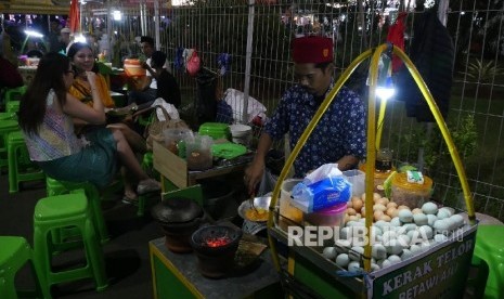 Seorang pedagang makanan khas Betawi, Kerak Telor, sedang menyiapakn pesanan pelanggannya di areal Pekan Raya Jakarta (PRJ) Selasa (13/6). 