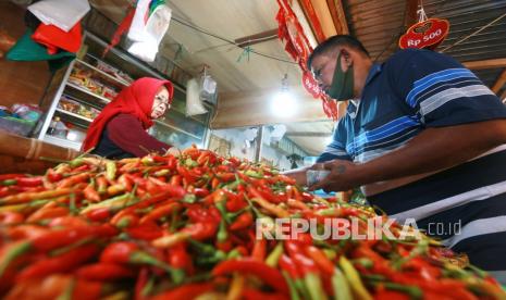 Seorang pedagang melayani pembeli cabai rawit di pasar. 