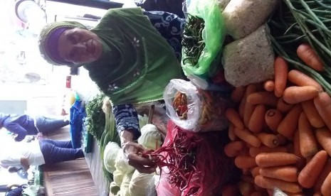 Seorang pedagang memegang dagangan cabai miliknya di sebuah pasar di Yogyakarta.