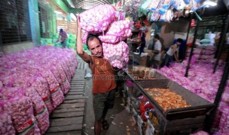  Seorang pedagang mengangkut bawang putih di Pasar Induk Kramat Jati, Selasa (26/3).  (Republika/Wihdan Hidayat)