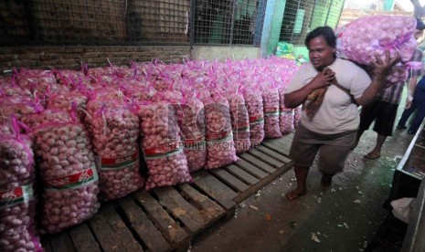  Seorang pedagang mengangkut bawang putih di Pasar Induk Kramat Jati, Selasa (26/3).  (Republika/Wihdan Hidayat)