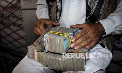 Seorang pedagang penukaran mata uang menghitung Afgani ketika orang-orang berkumpul untuk menarik uang dari sebuah bank di Kabul, Afghanistan, Ahad (12/9). Dewan Bank Dunia disebut mendukung transfer 280 juta dolar AS ke Afghanistan. Ilustrasi.