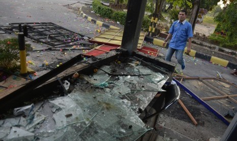 Seorang pegawai Rektorat Universitas Riau melintasi pos keamanan yang rusak parah akibat bentrokan di Gedung Fakultas Ilmu Sosial dan Politik Universitas Riau, di Kota Pekanbaru, Jumat (6/10). 