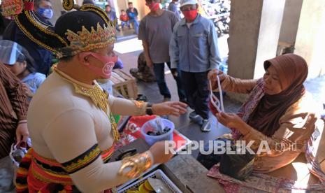 Seorang pejabat Pemkab Temanggung memberikan masker kapada padagang saat sosialisasi gerakan 3M (memakai masker, mencuci tangan, dan menjaga jarak) di Pasar Legi Parakan, Temanggung, Jawa Tengah, Ahad (6/9/2020). Sejumlah pejabat di kabupaten Temanggung bersama puluhan seniman memakai pakaian pewayangan mensosialisasikan gerakan 3M ke sejumlah pasar tradisonal guna mencegah penyebaran COVID-19.