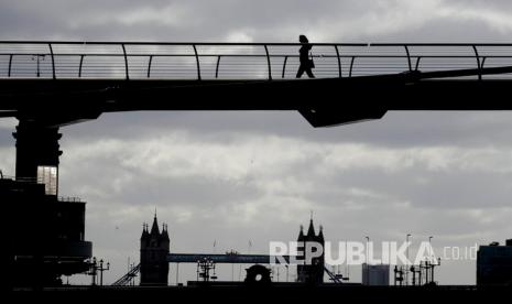 Seorang pejalan kaki berjalan melintasi Jembatan Milenium di atas sungai Thames di London, Senin (11/5). Perdana Menteri Inggris Boris Johnson mengumumkan kembali membuka aktivitas perkantoran setelah masa lockdown akibat pandemi Covid-19. (ilustrasi)