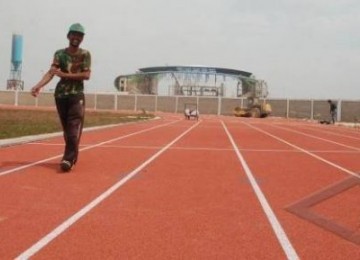 Seorang pekerja berjalan di atas lintasan lari di Stadion atletik Jakabaring Palembang, Selasa (13/9).