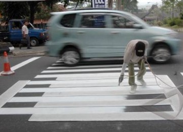 Seorang pekerja melakukan proses pengecatan jalan di jalur utama kota Temanggung, Jawa Tengah.