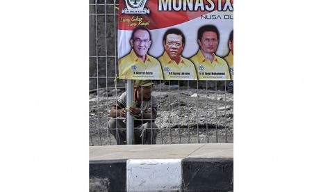   Seorang pekerja memasang bendera dan spanduk Musyawarah Nasional (Munas) IX Partai Golkar di pagar pembatas Tol Bali Mandara saat persiapan kegiatan tersebut di Nusa Dua, Bali, Jumat (28/11).  (Antara/Nyoman Budhiana)