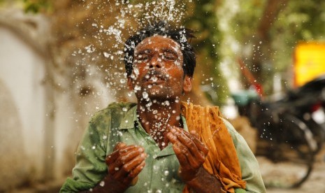 Seorang pekerja memercikkan air ke wajahnya di tengah cuaca panas di Prayagraj, Uttar Pradesh, India, Kamis (13/6). Cuaca panas ekstrem melanda India dengan rata-rata suhu mencapai 48 derajat Celcius. 