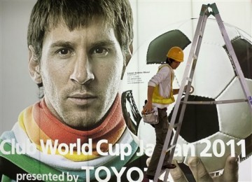 Seorang pekerja menaiki tangga saat membenahi poster Piala Dunia antar-Klub 2011 dengan latar potret Lionel Messi di Tokyo, Jepang, Kamis (24/11) 