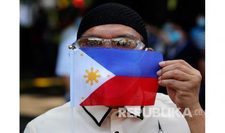 Seorang pekerja pemerintah Filipina menunjukkan sebuah bendera saat pandemi virus corona di daerah kumuh Manila, Filipina.