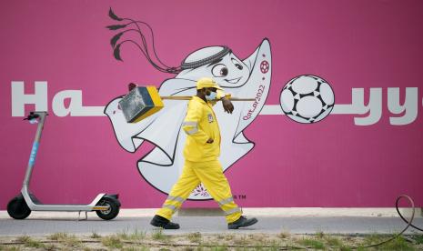 Negara-Negara Musilm Usulkan Ban Lengan Anti Islamofobia di Piala Dunia. Foto: Seorang pekerja publik berjalan di depan dinding yang menunjukkan ilustrasi maskot Piala Dunia FIFA Qatar 2022 mendatang La