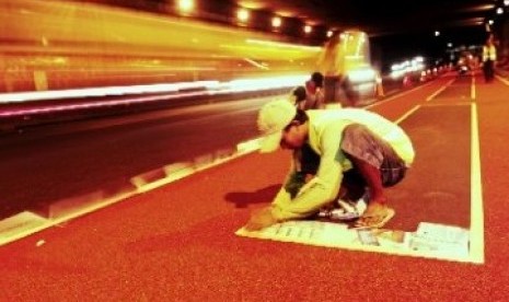 Seorang pekerja tampak menyelesaikan jalur busway (ilustrasi).