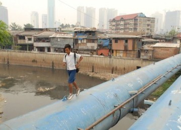 Seorang pelajar berlari melintasi pipa air milik PAM Jaya di atas Kali Krukut, Bendungan Hilir, Jakarta. 