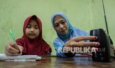 Seorang pelajar didampingi orang tua mengikuti kegiatan belajar mengajar (KBM) melalui siaran radio Lembaga Penyiaran Publik Lokal (LPPL) Radio Kota Batik dari gurunya di Pekalongan, Jawa Tengah, Rabu (2/9/2020). Pemerintah setempat bersama LPPL Radio Kota Batik memfasilitasi guru untuk mengajar dengan cara siaran pendidikan sebagai penunjang proses kegiatan pembelajaran jarak jauh saat pandemi COVID-19.