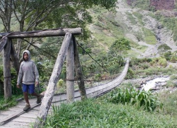 Seorang pelajar SMP tengah melintasi jembatan kayu di kaki bukit Yammo. Di sekitar jembatan ini kerap terjadi baku tembak antara aparat keamanan dan kelompok bersenjata.