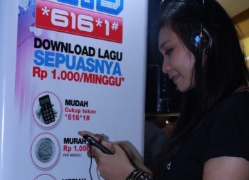 Seorang pelanggan Telkomsel sedang memanfaatkan ponselnya untuk mendengarkan lagu yang telah diunduh melalui LangitMusik HITS!.