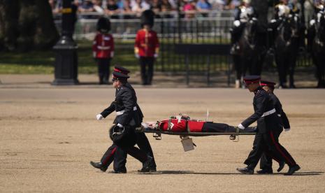 Seorang pemain trombone dari band militer dibawa dengan tandu setelah pingsan selama Tinjauan Kolonel, latihan terakhir Trooping the Colour, parade ulang tahun tahunan Raja, di Horse Guards Parade di London, Sabtu, 10 Juni 2023.