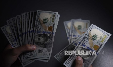 Seorang pembeli menghitung uang Dolar Amerika Serikat yang ditukarnya di gerai penukaran valuta asing, Jakarta, Senin.