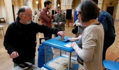 Seorang pemili Prancis memberikan suaranya dalam pemilu presiden putaran kedua di Lyon, Prancis, Ahad (7/5).