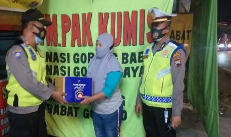 Seorang pemilik warung tenda menerima bantuan sosial dari anggota Polres Semarang di sela kegiatan patroli dan edukasi PPKM Darurat kepada para pedagang kaki lima (PKL) dan warung tenda di kawasan Alun Alun Lama, Ungaran, Kabupaten Semarang.