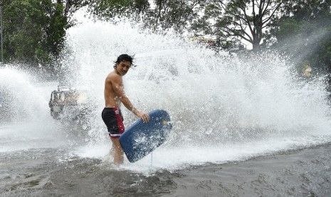  Seorang pemuda terciprat air dari mobil yang melintas banjir di Sydney, Australia, Ahad (9/2). Australia mengalami cuaca ekstrem beberapa pekan terakhir.