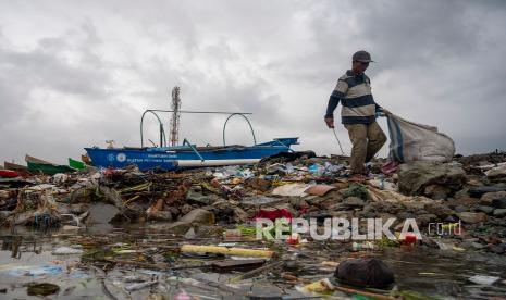 Seorang pemulung mencari plastik bekas di tumpukan sampah. 