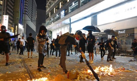 Seorang pendemo membakar foto Presiden China Xi Jinping dalam protes di Hong Kong, Selasa (1/10). Polisi menembak seorang pendemo di dada dari jarak dekat hingga berdarah di bahu.