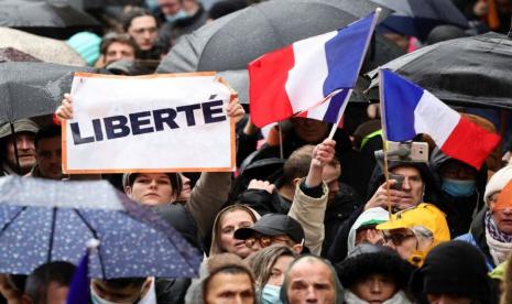 Seorang pendemo memegang tanda bertuliskan Kebebasan ketika orang-orang menghadiri demonstrasi memprotes RUU yang akan mengubah izin kesehatan infeksi Covid-19 di Paris, Prancis, 8 Januari 2022. Para pengunjuk rasa anti vaksin telah turun ke jalan-jalan di seluruh Eropa Barat sebagai protes terhadap persyaratan vaksin Covid-19 di negaranya. 