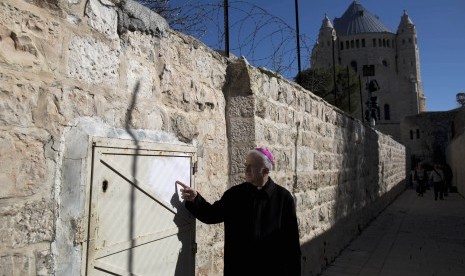 Seorang pendeta menunjukkan bekas graffiti anti-kristen di Dormition Abbey, Kota Tua, Jerusalem, Ahad (17/1). 