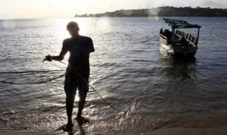 Seorang penduduk Lamu, Kenya, menarik perahu ke tepian pantai.