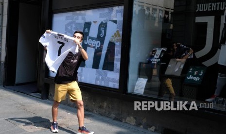 Seorang pendukung Juventus menunjukkan kaos Cristiano Ronaldo di luar toko Juve di via Garibaldi, Turin (11/7).